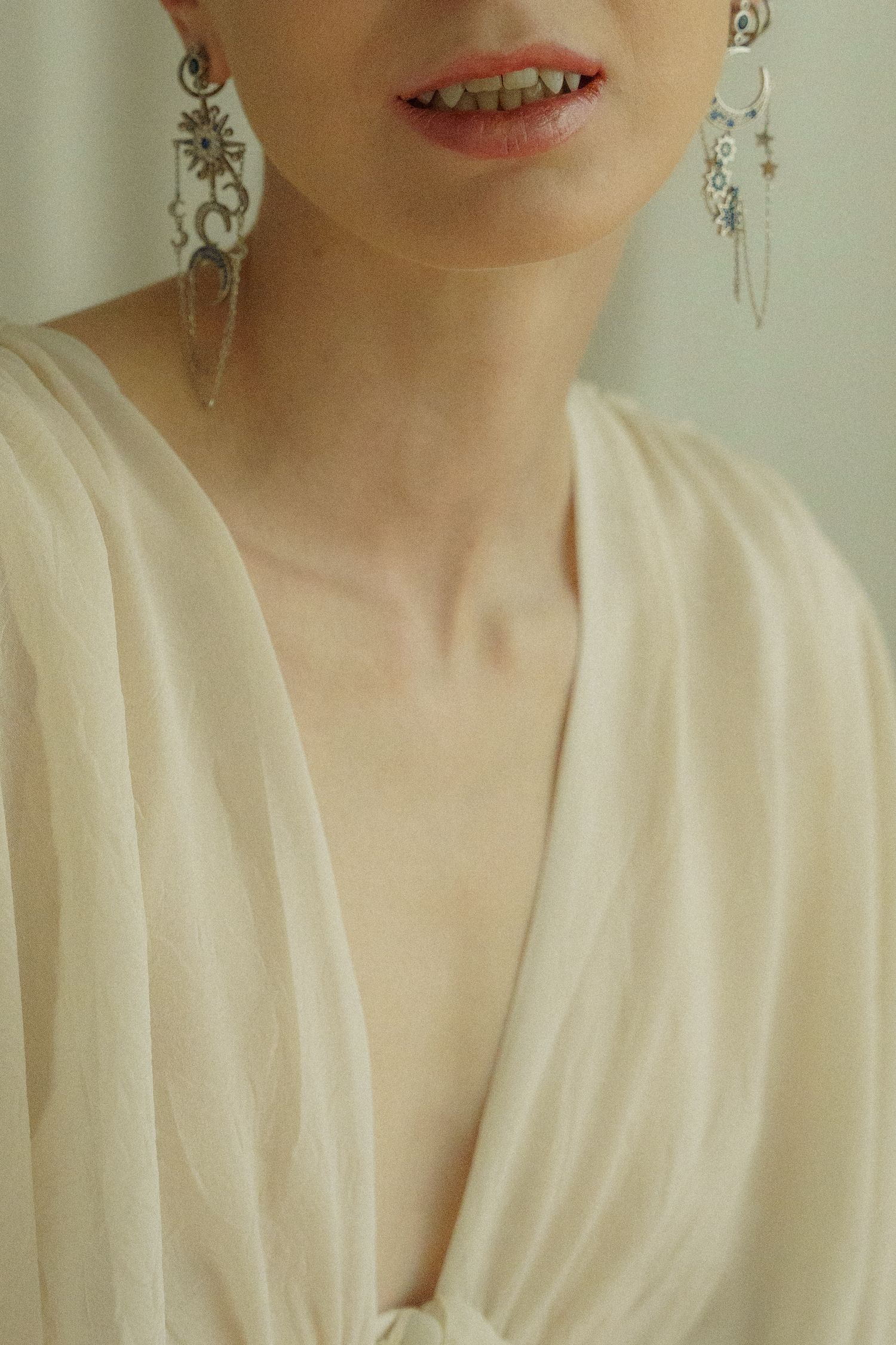 Close-up fashion portrait featuring pleated white fabric and delicate jewelry.