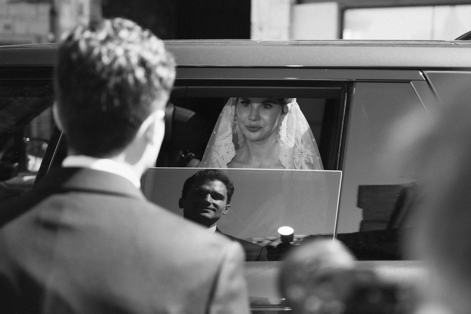 Black and white image of guests seated in cars during what appears to be a drive-in ceremony.