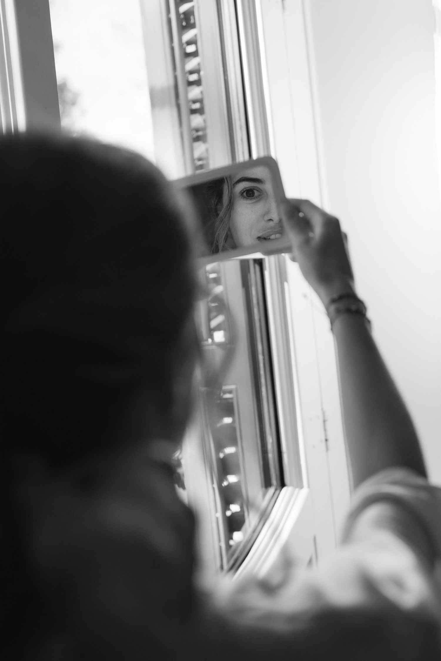 Black and white image of preparation in dressing room with mirror reflections.