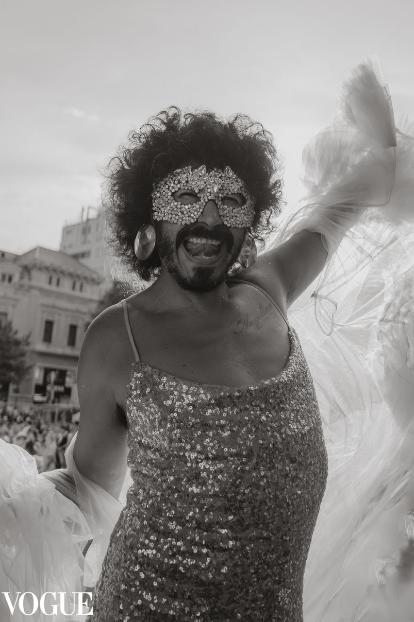 Person in a sparkly dress and sunglasses dancing with flowing white fabric.