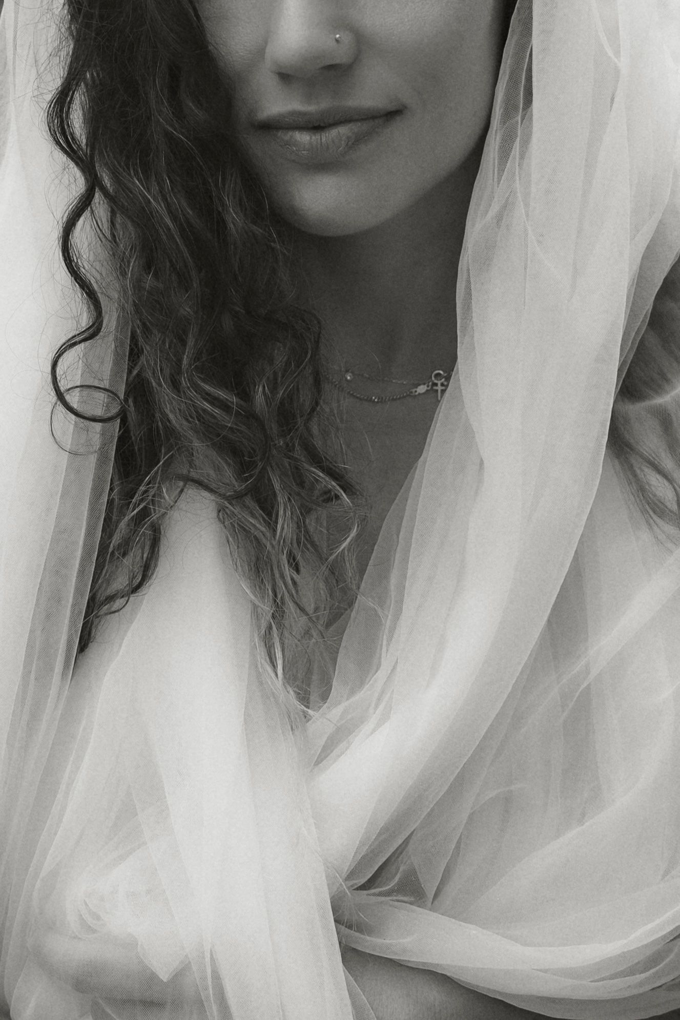 Artistic portrait featuring delicate white veil fabric and soft lighting.