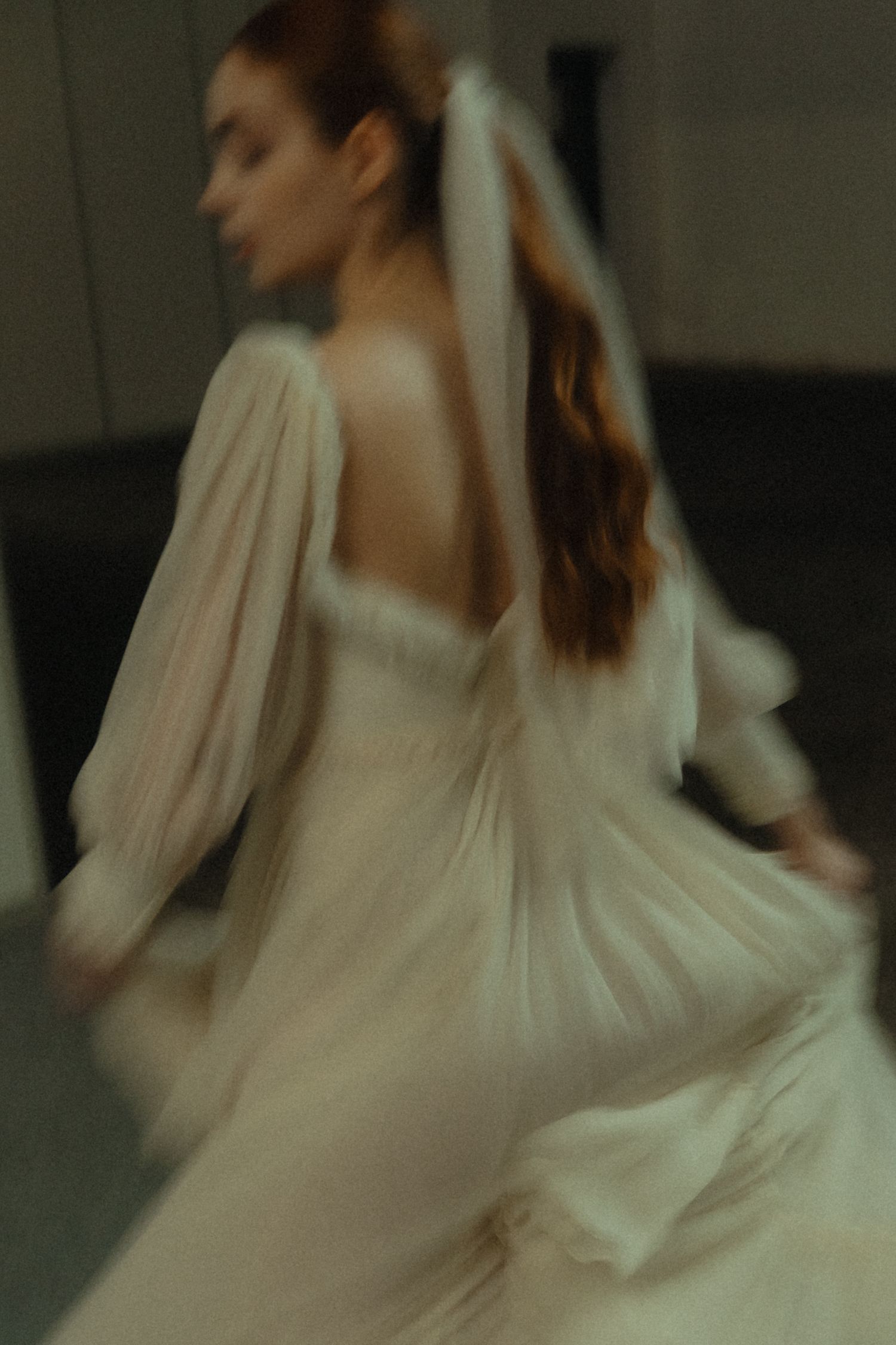 Motion-blurred portrait of a person in flowing white dress with long sleeves.
