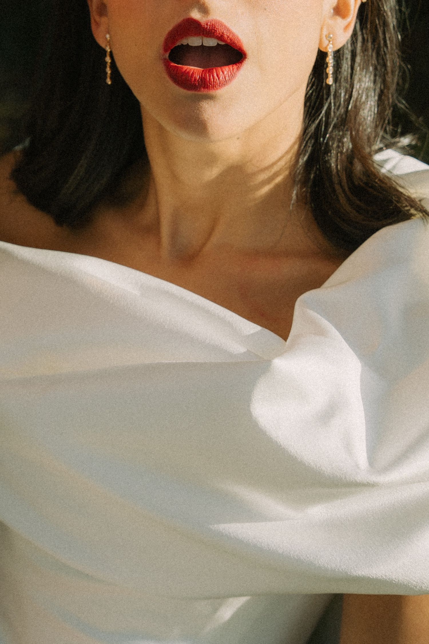 Artistic close-up of bright red lipstick against white fabric background.