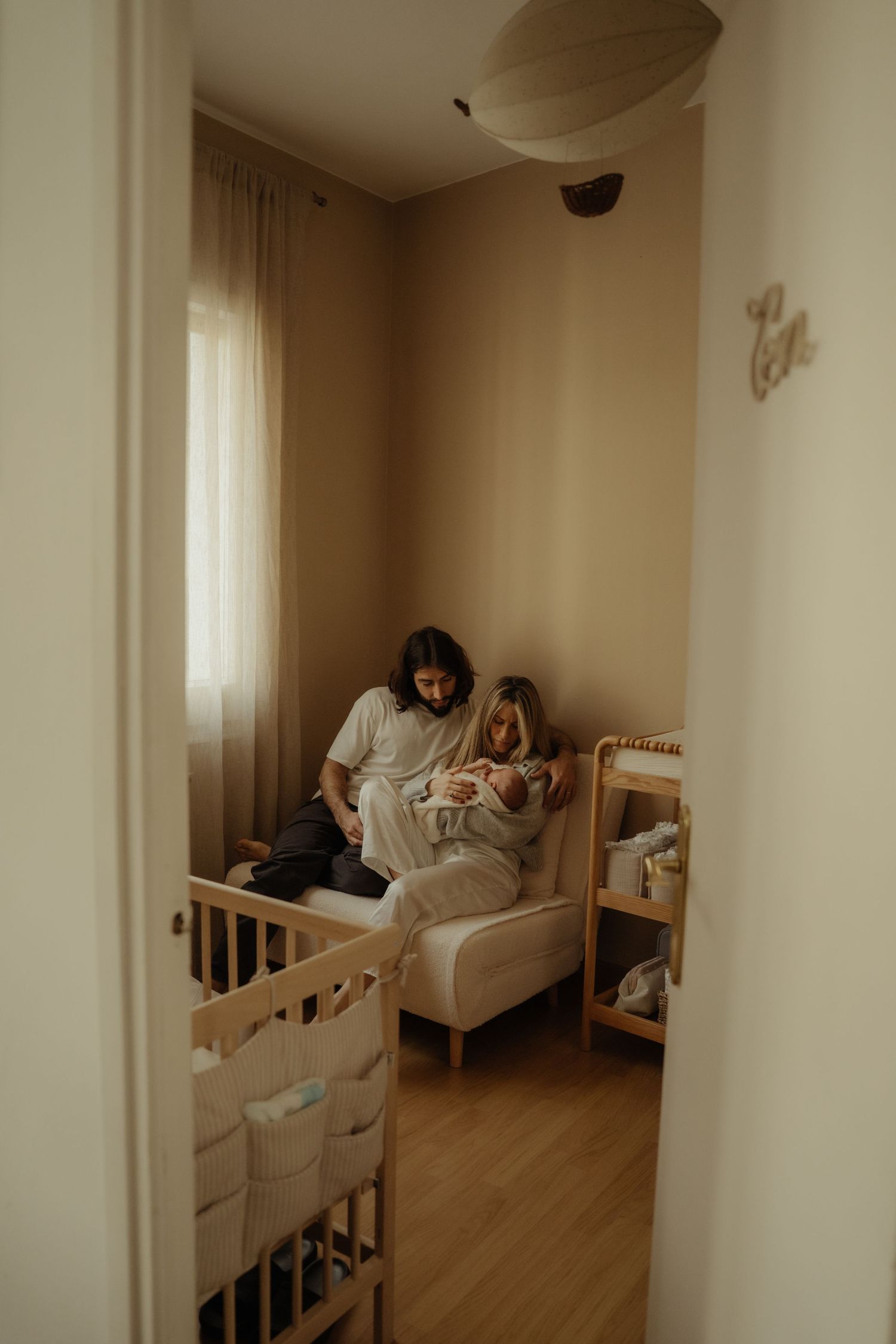 Cozy nursery interior with wooden crib and soft neutral decor in natural light.