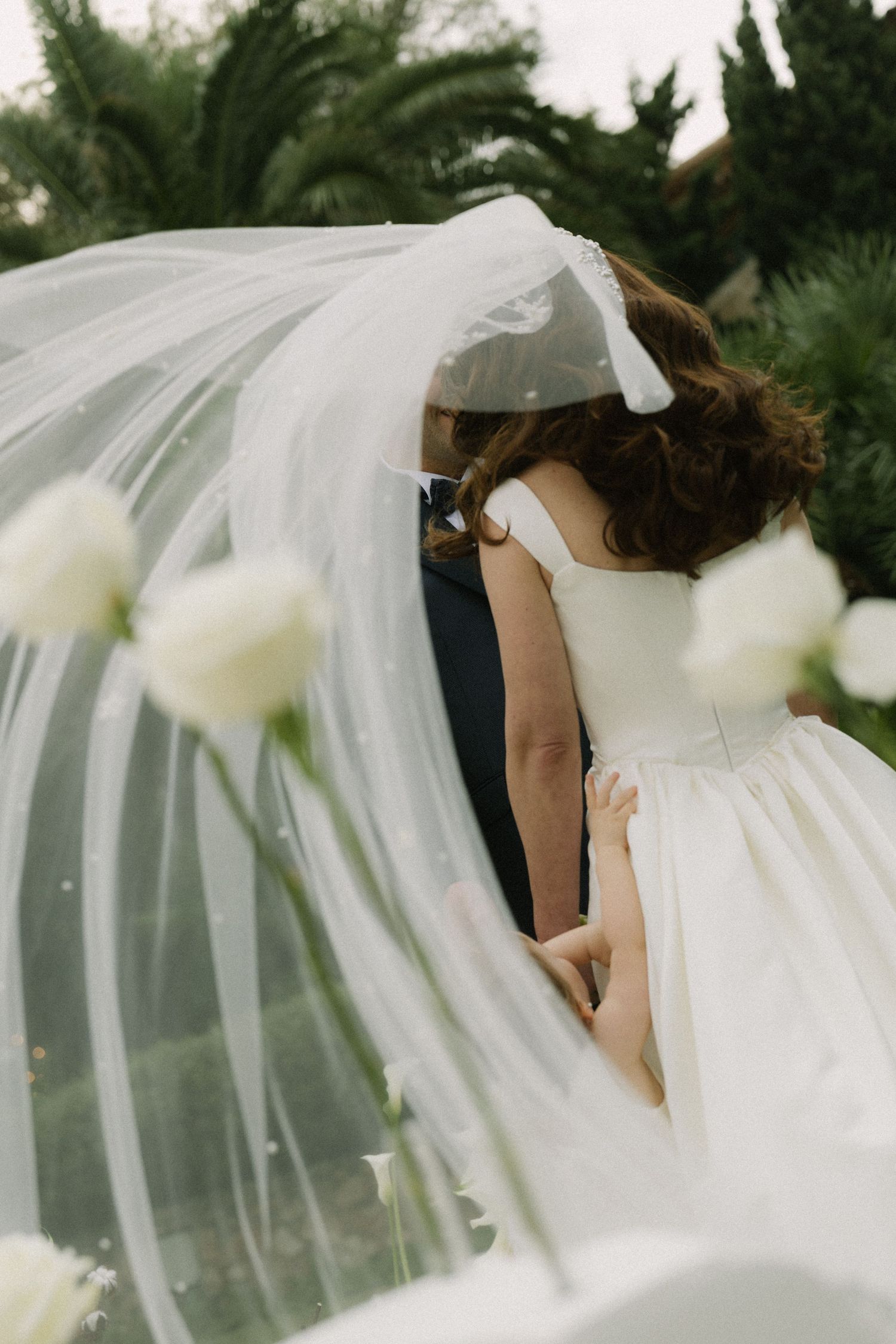 Flowing white wedding veil billowing in the breeze against a natural outdoor backdrop.