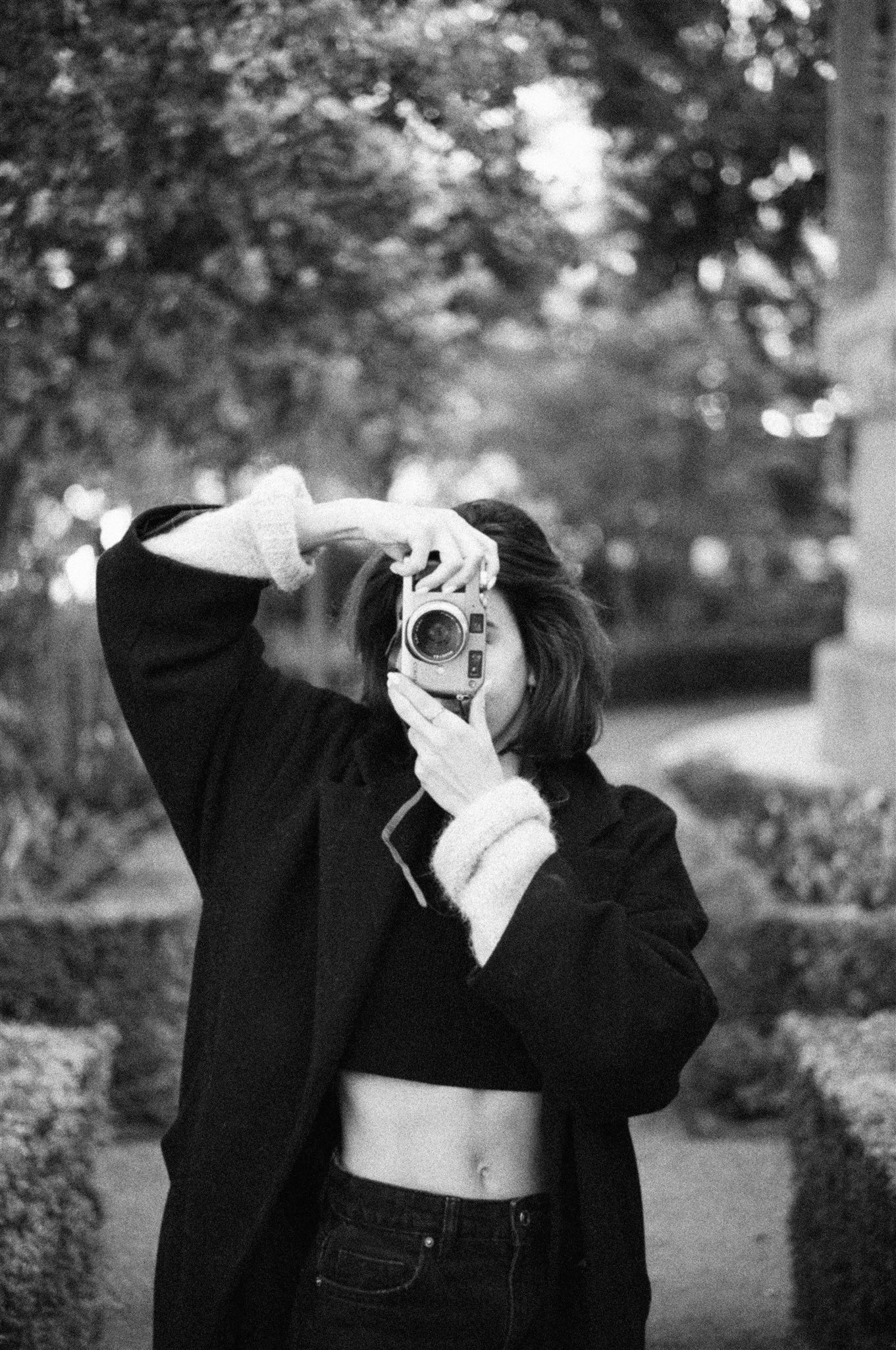 Black and white photo series of someone taking pictures with a vintage camera outdoors.