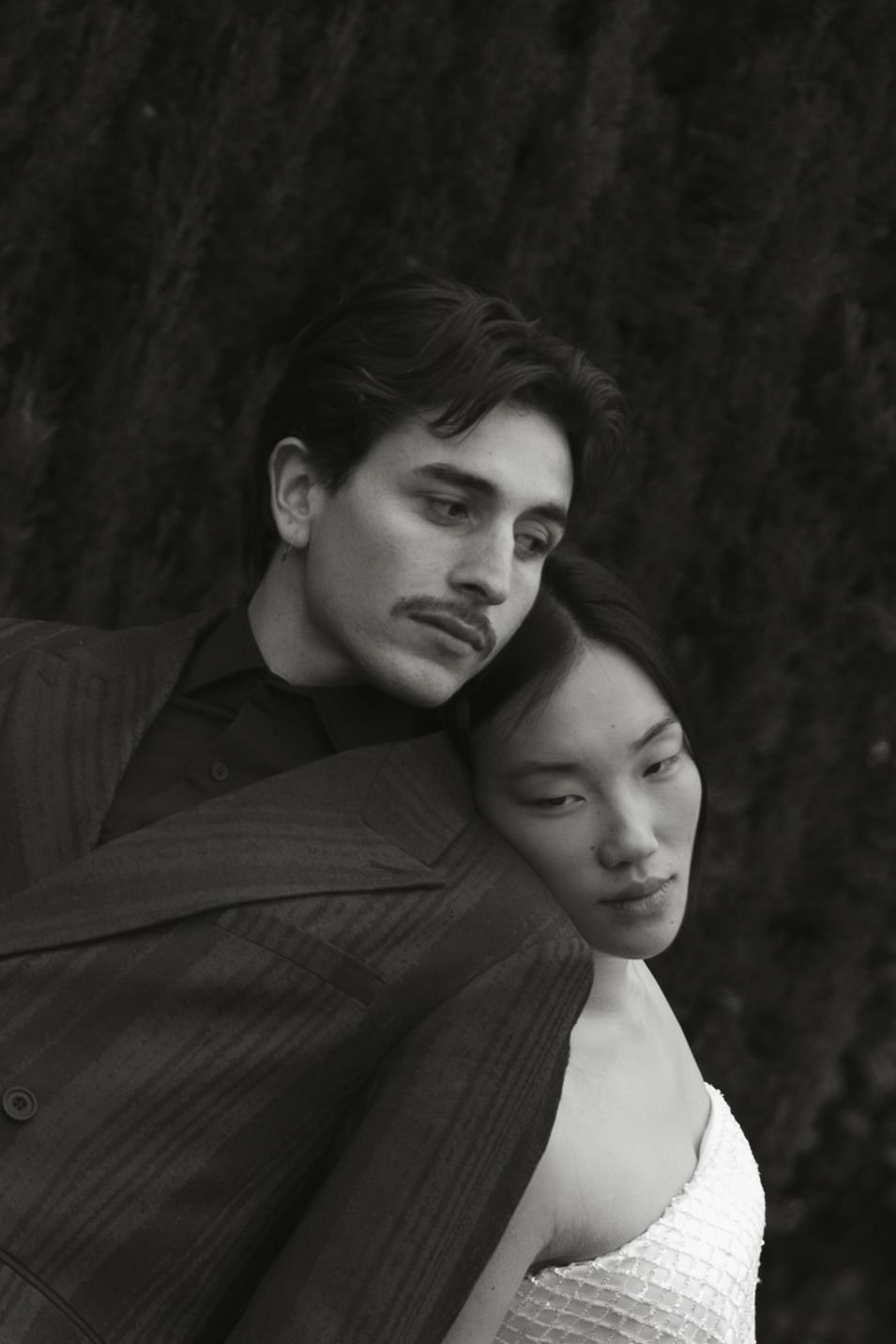 Black and white portrait of two people in formal attire posing intimately.