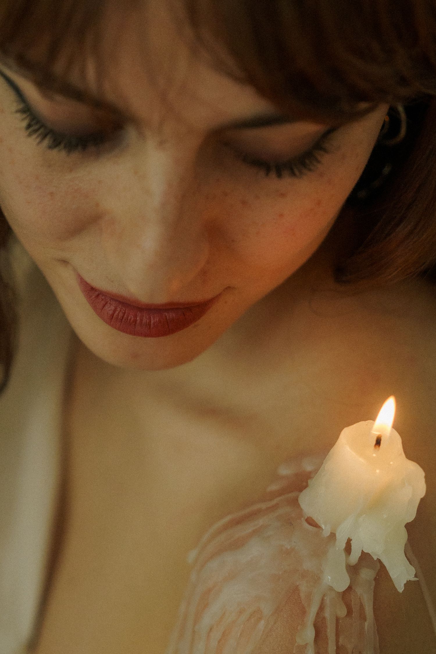 Intimate portrait with melting candle creating dramatic lighting effects.