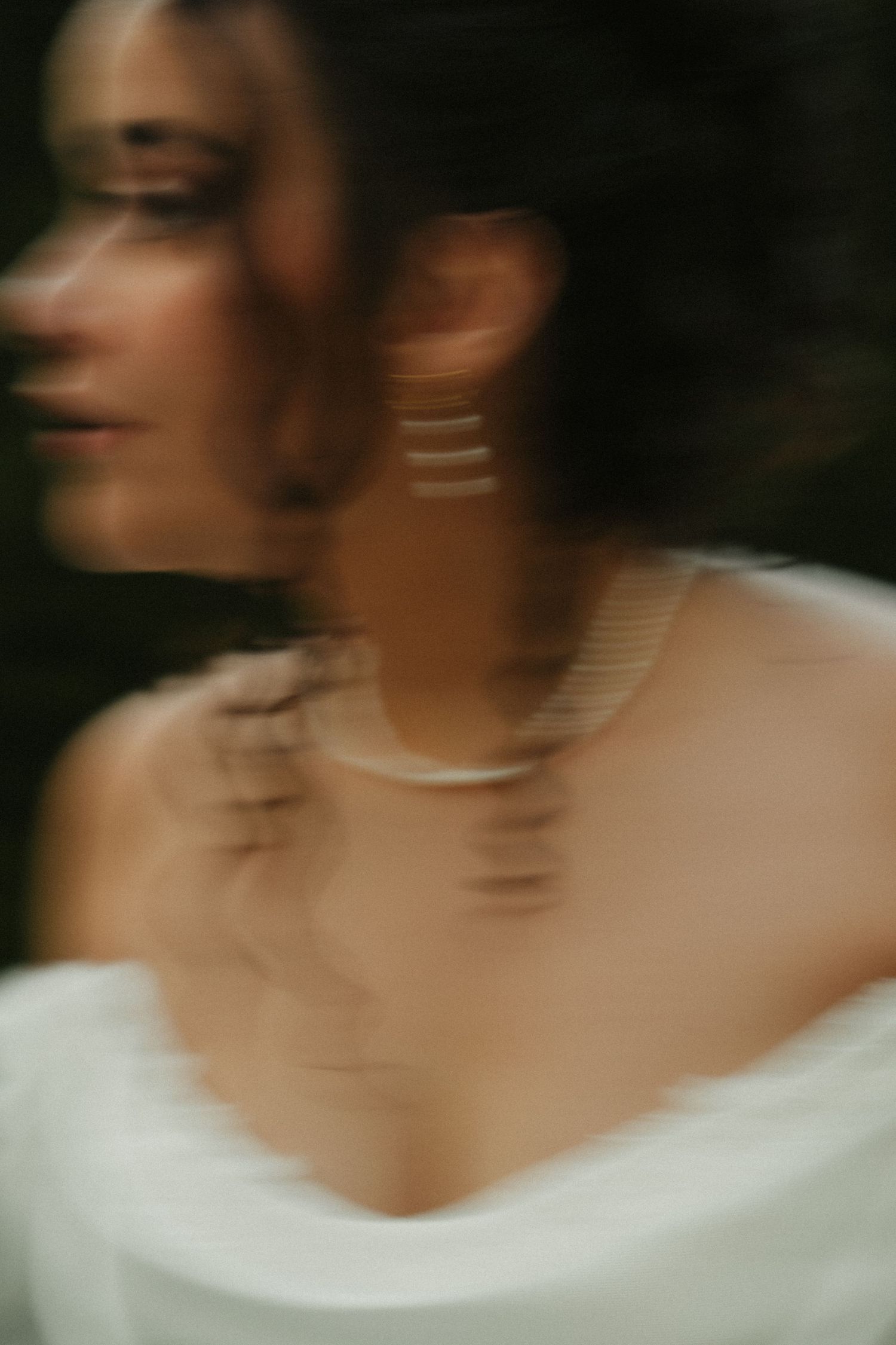 A blurred motion sequence of a person wearing a white top against a dark background creates an artistic effect.