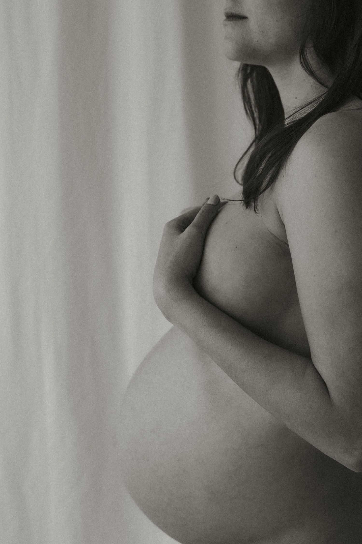 Black and white silhouette showing a pregnant woman's belly against a light background.