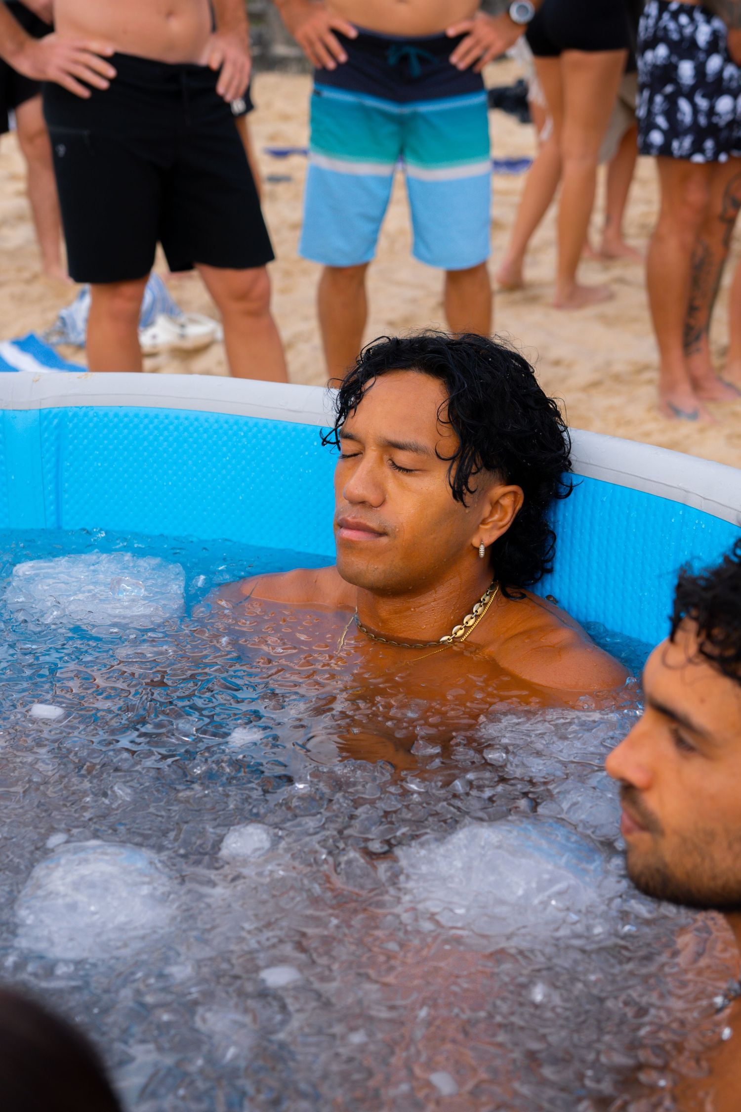 People relaxing in an ice bath tub during an outdoor wellness event.