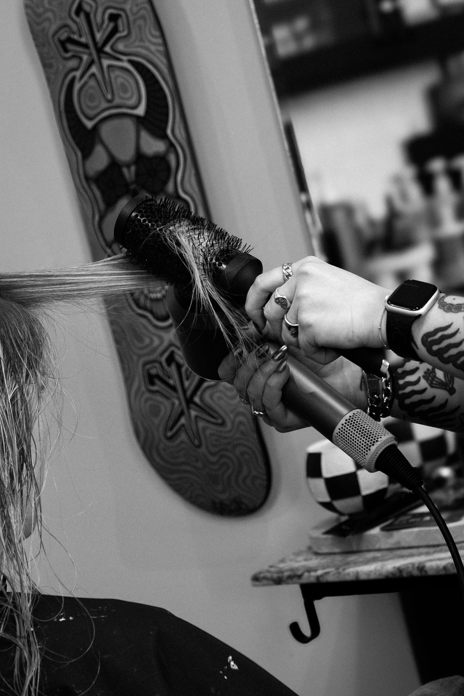 Close-up black and white shot of hands holding hair styling tools against a decorative wall.