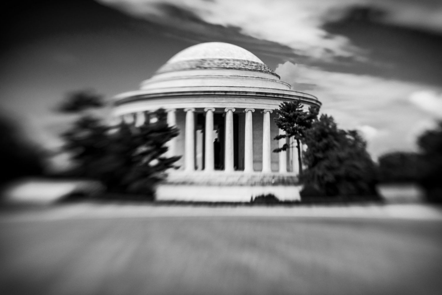Black and white photo of the Jefferson Memorial with columns and dome surrounded by trees.