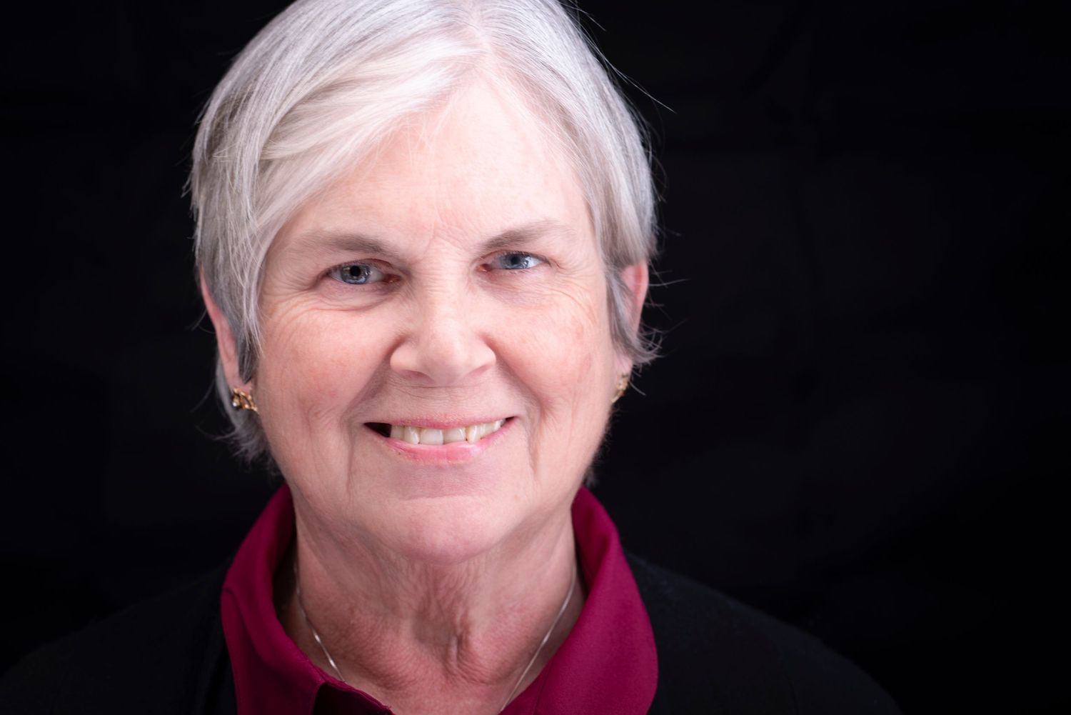 Color portrait of an older woman with dramatic lighting.