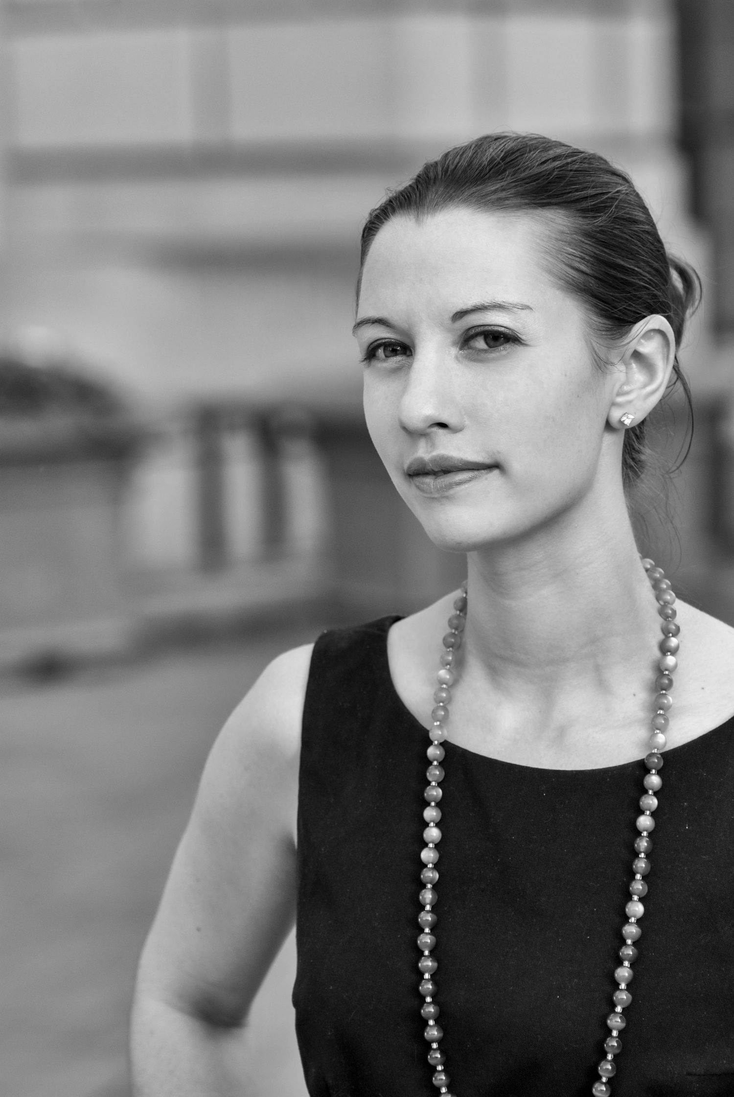 Elegant profile shot with statement necklace and sleeveless black dress.