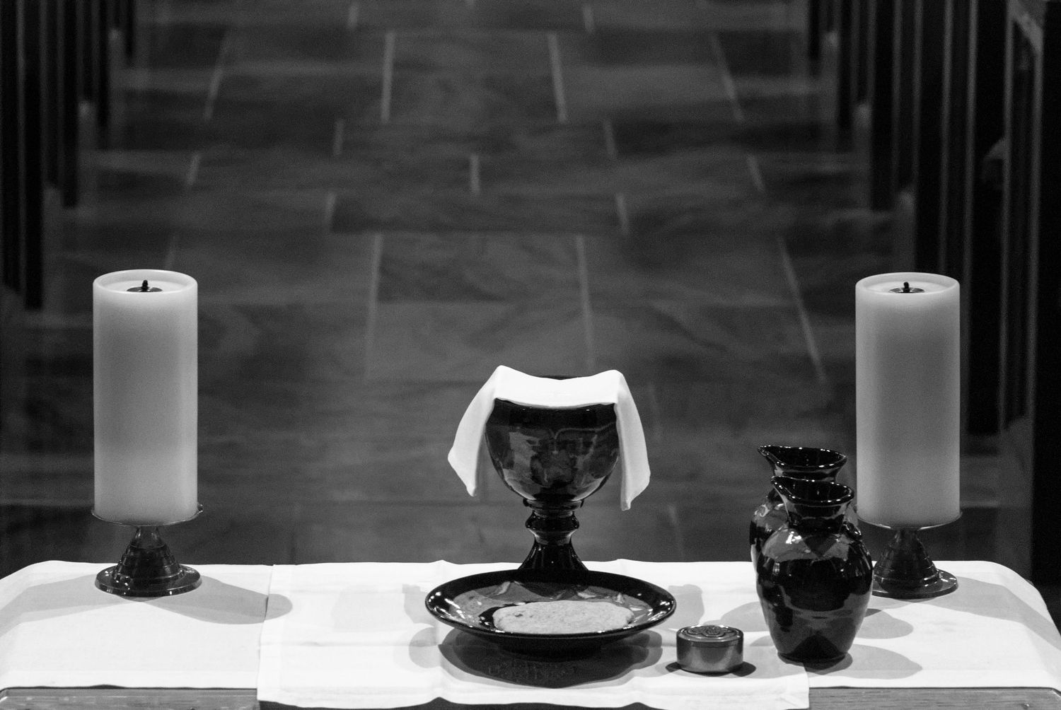 Church altar setup with communion elements and white candles in black and white photography.