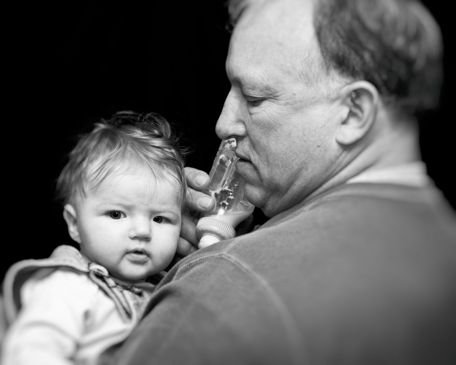 Black and white portrait of tender moments between grandfather and baby.