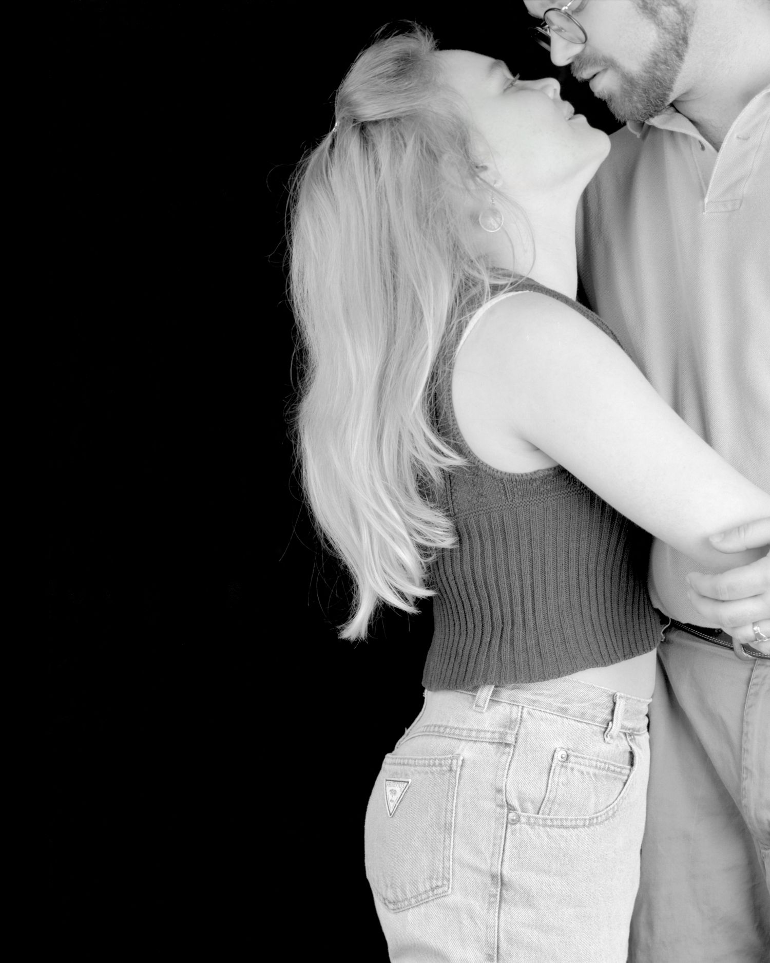 Black and white artistic photo series showing romantic couple embracing in intimate dance-like poses against dark backdrop.