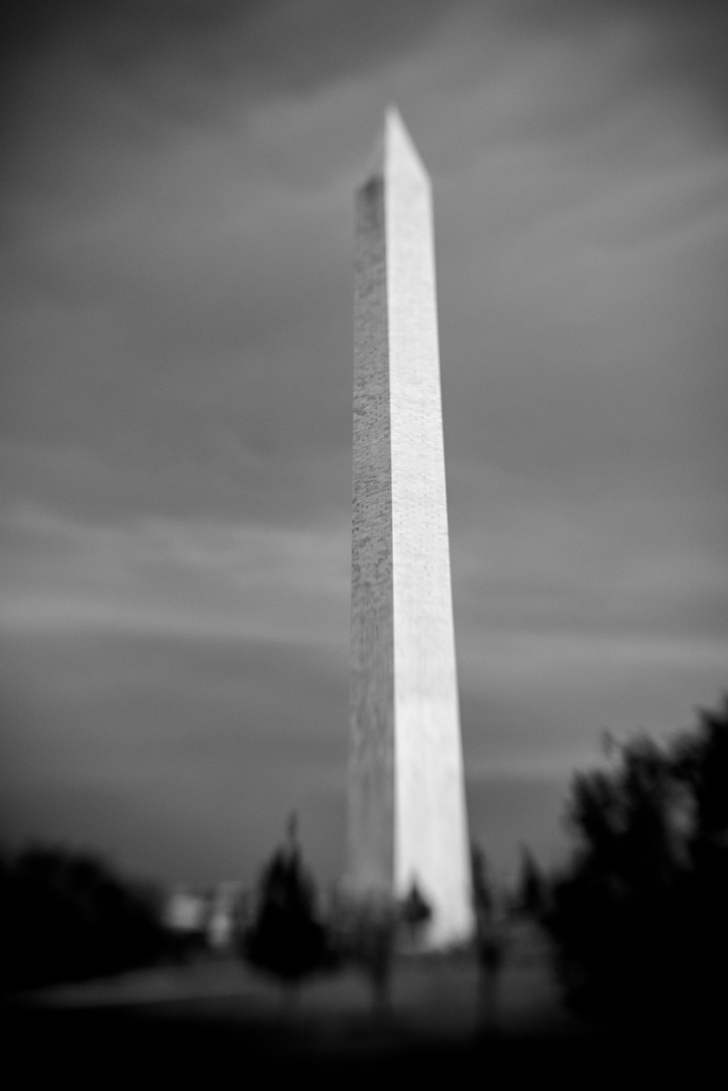 Black and white photo of the Washington Monument obelisk against a dramatic cloudy sky.