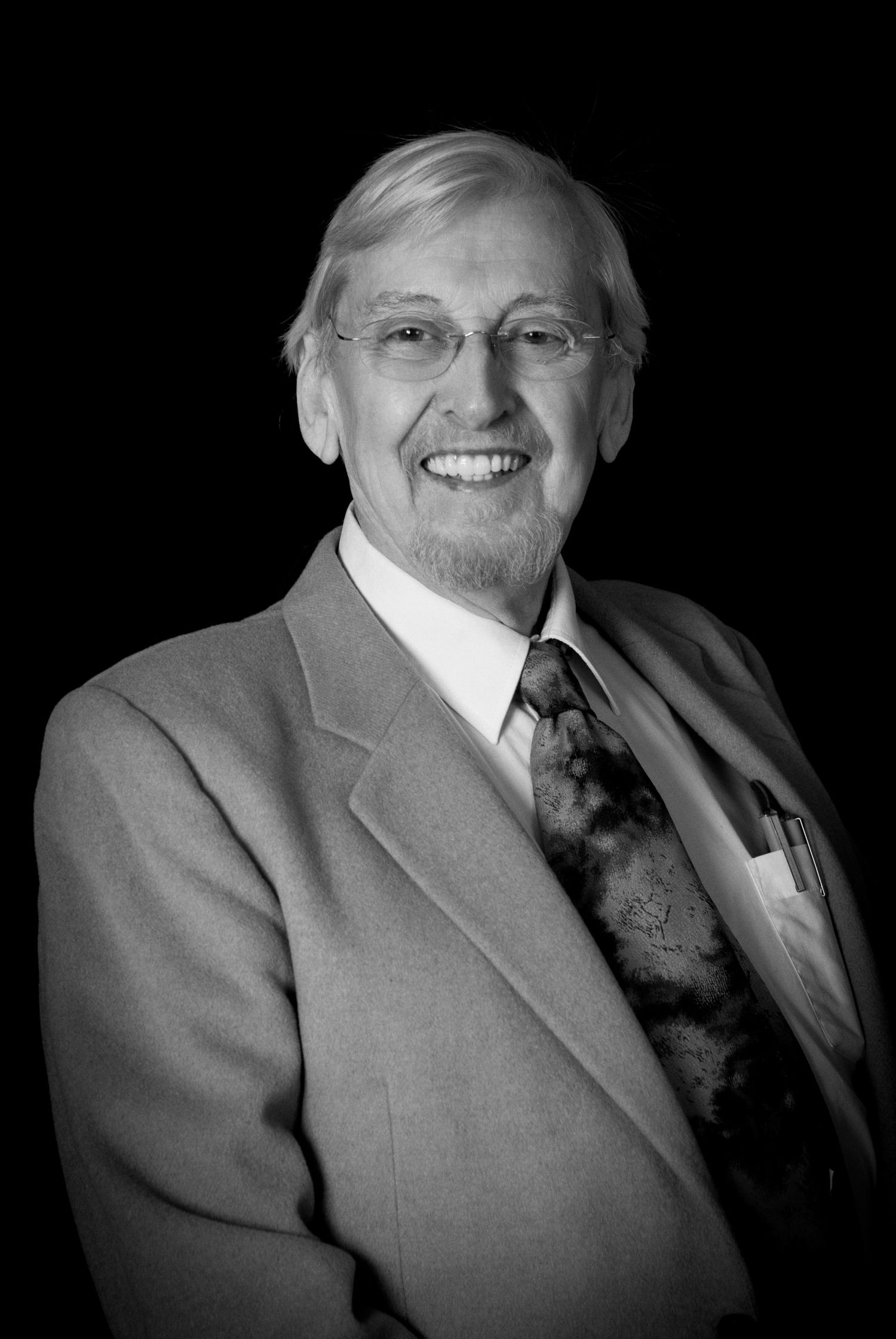 Professional portrait in gray suit and tie against black background showing various expressions.