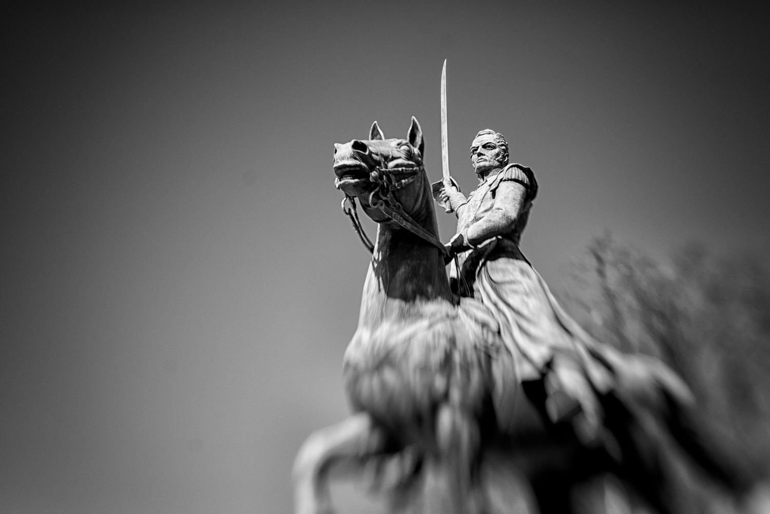 Black and white photo of an equestrian statue of a soldier on horseback holding a sword aloft.