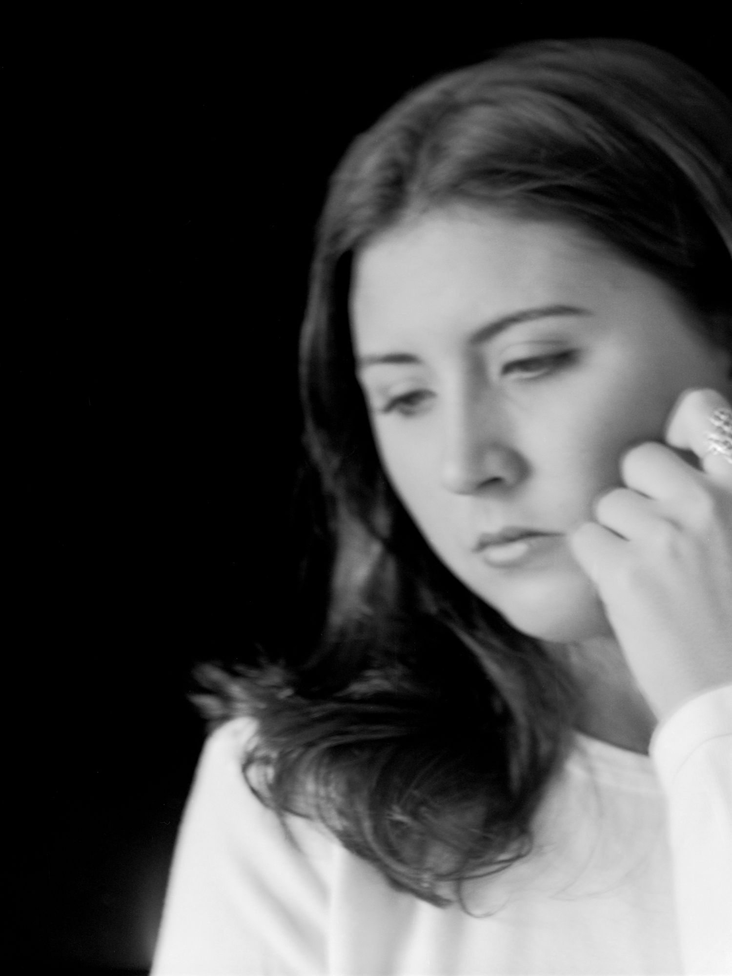 Artistic black and white portrait showing soft contemplative expressions against dark background.