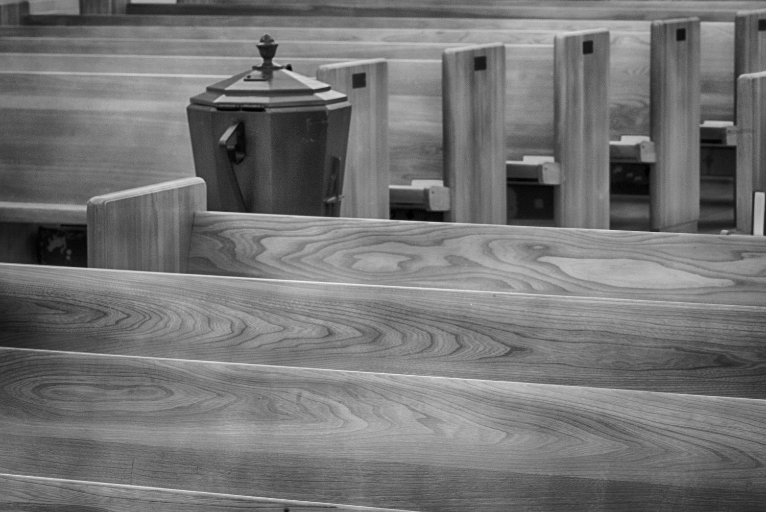 Black and white detail of wooden church pews with Baptismal font  St Lukes Episcopal Church Bethesda
