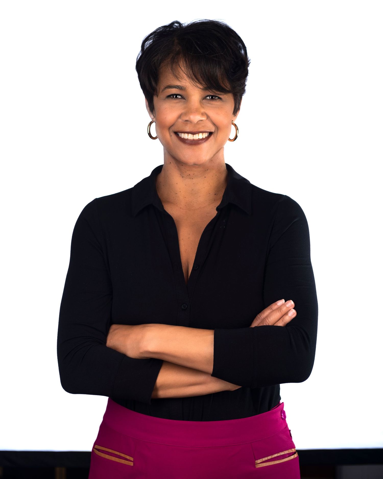 Professional portrait of a woman in black top with crossed arms against white background.