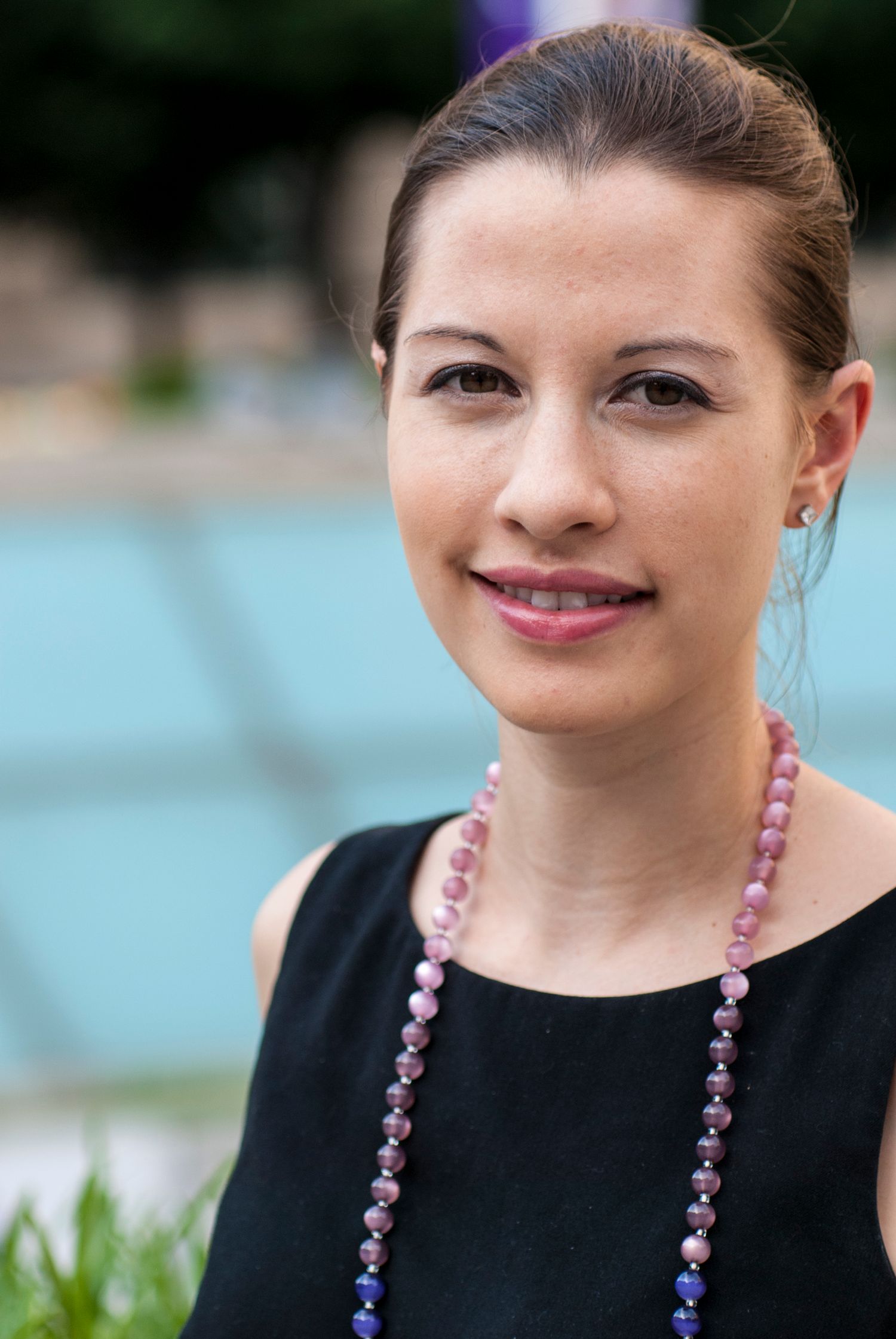 Portrait series showing young woman in black attire with pink and purple beaded necklace, shot outdoor