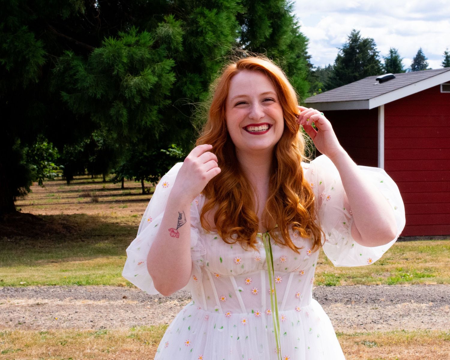 A white lace dress photographed in a sunny outdoor setting with trees in the background.