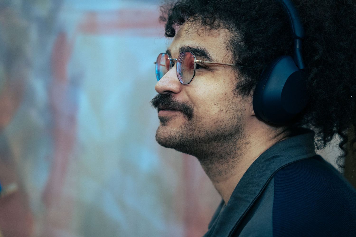 Profile view of person wearing headphones in dim lighting.