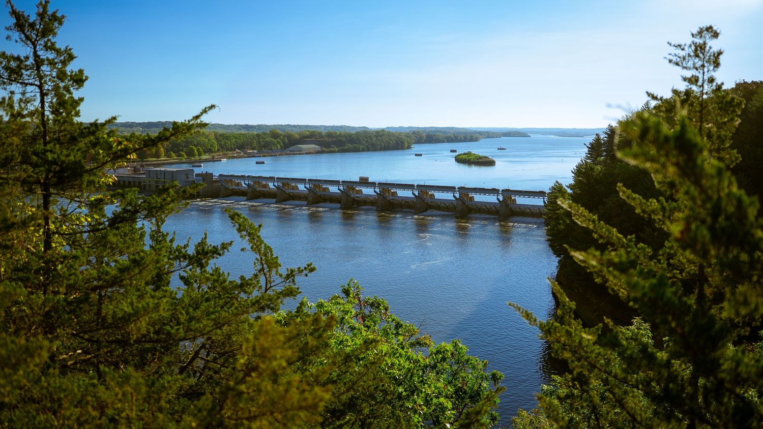 Panoramic view of a lake surrounded by pine trees and rocky coastline.