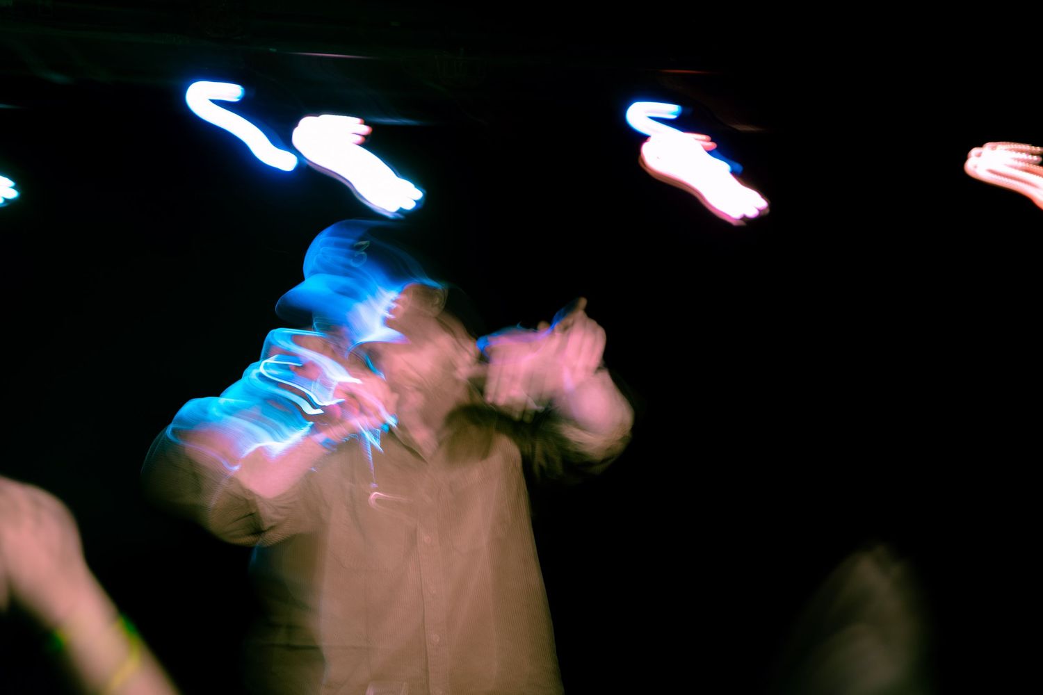 Abstract light trails creating blue and pink streaks against a dark background.