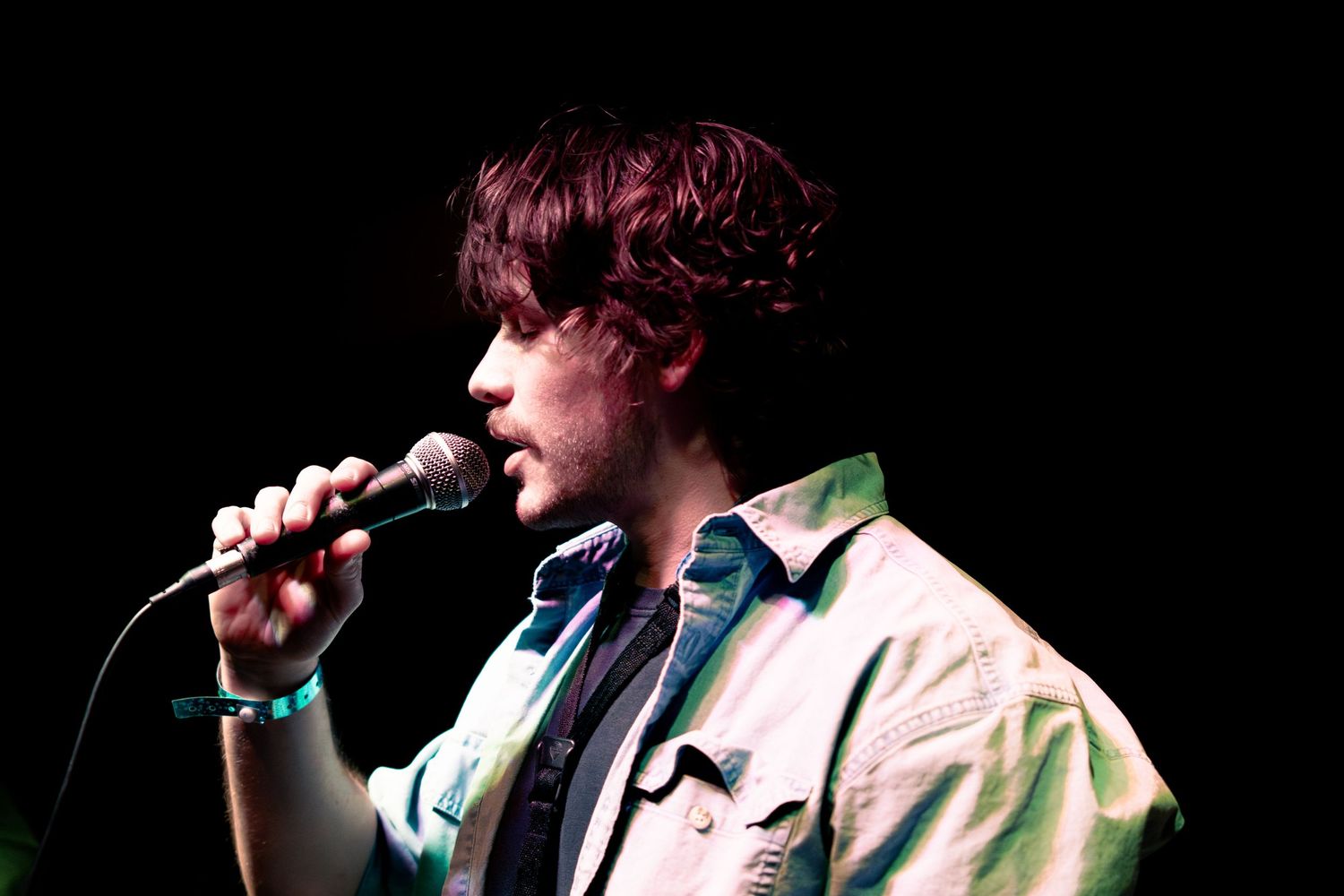 A performer sings passionately into a microphone on stage during a live musical performance.