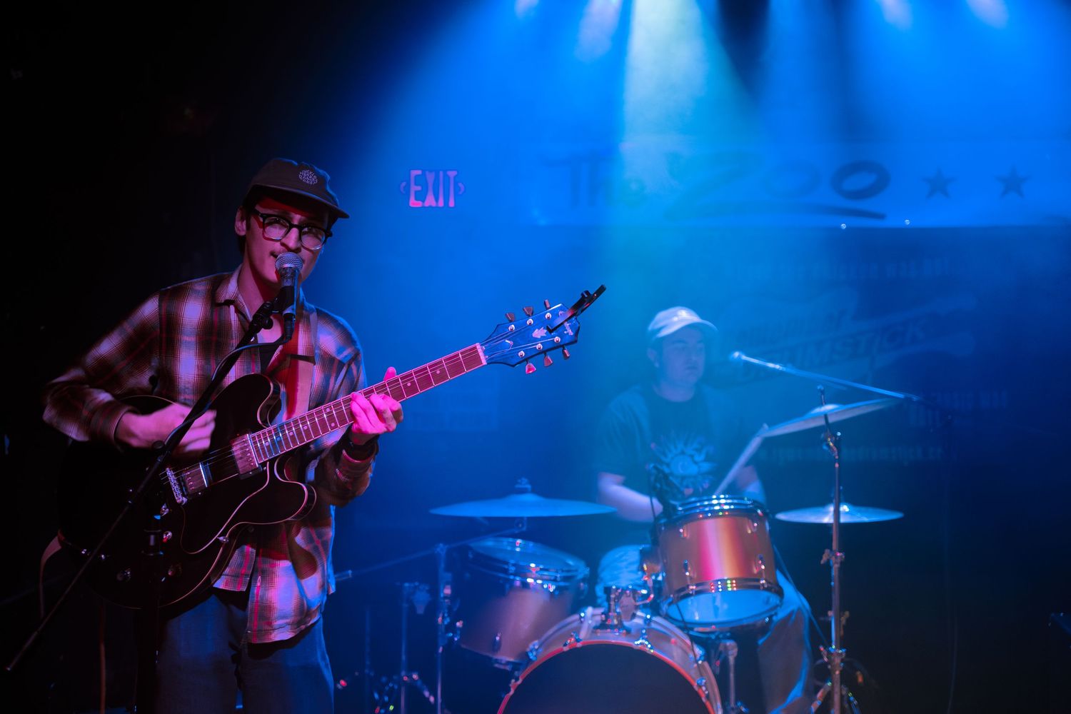Musicians performing on a dimly lit stage with blue spotlights and fog effects.