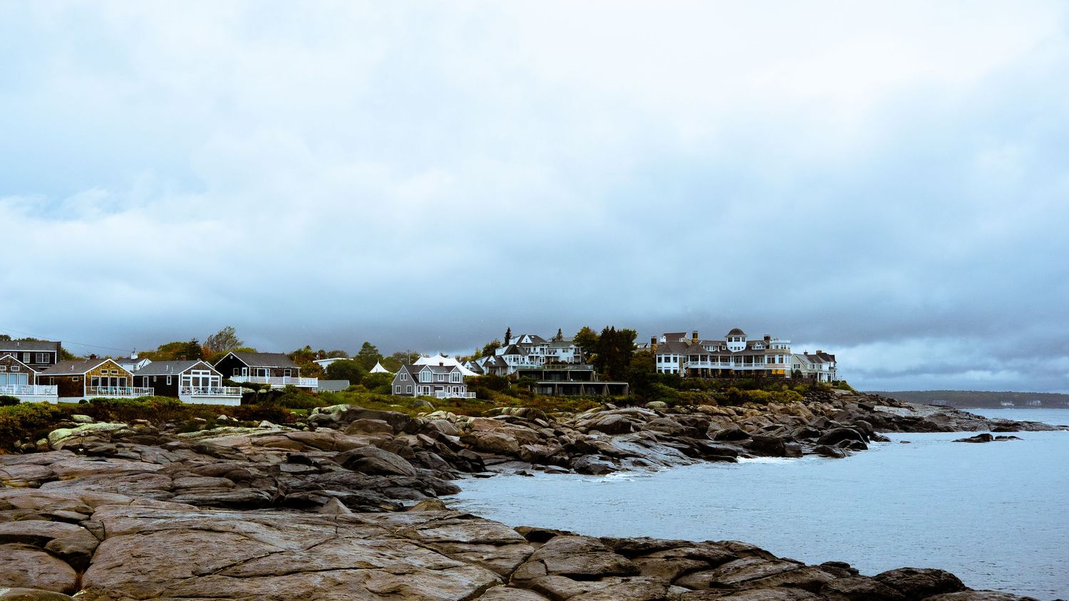 Panoramic view of a rocky coastline with houses and buildings dotting the shore.
