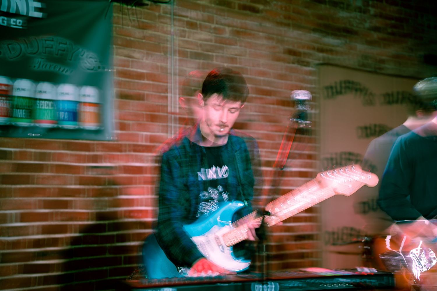 A series of blurred motion shots showing someone performing skateboarding tricks against a brick wall background.
