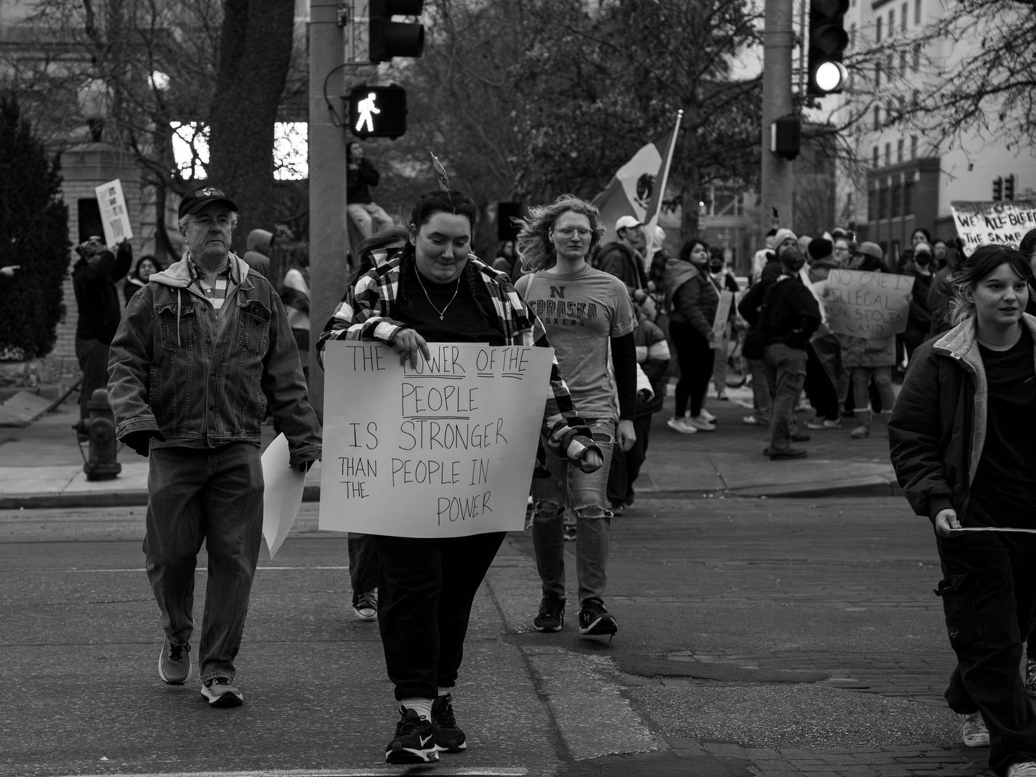 Black and white photo of protesters marching on a city street holding protest signs.