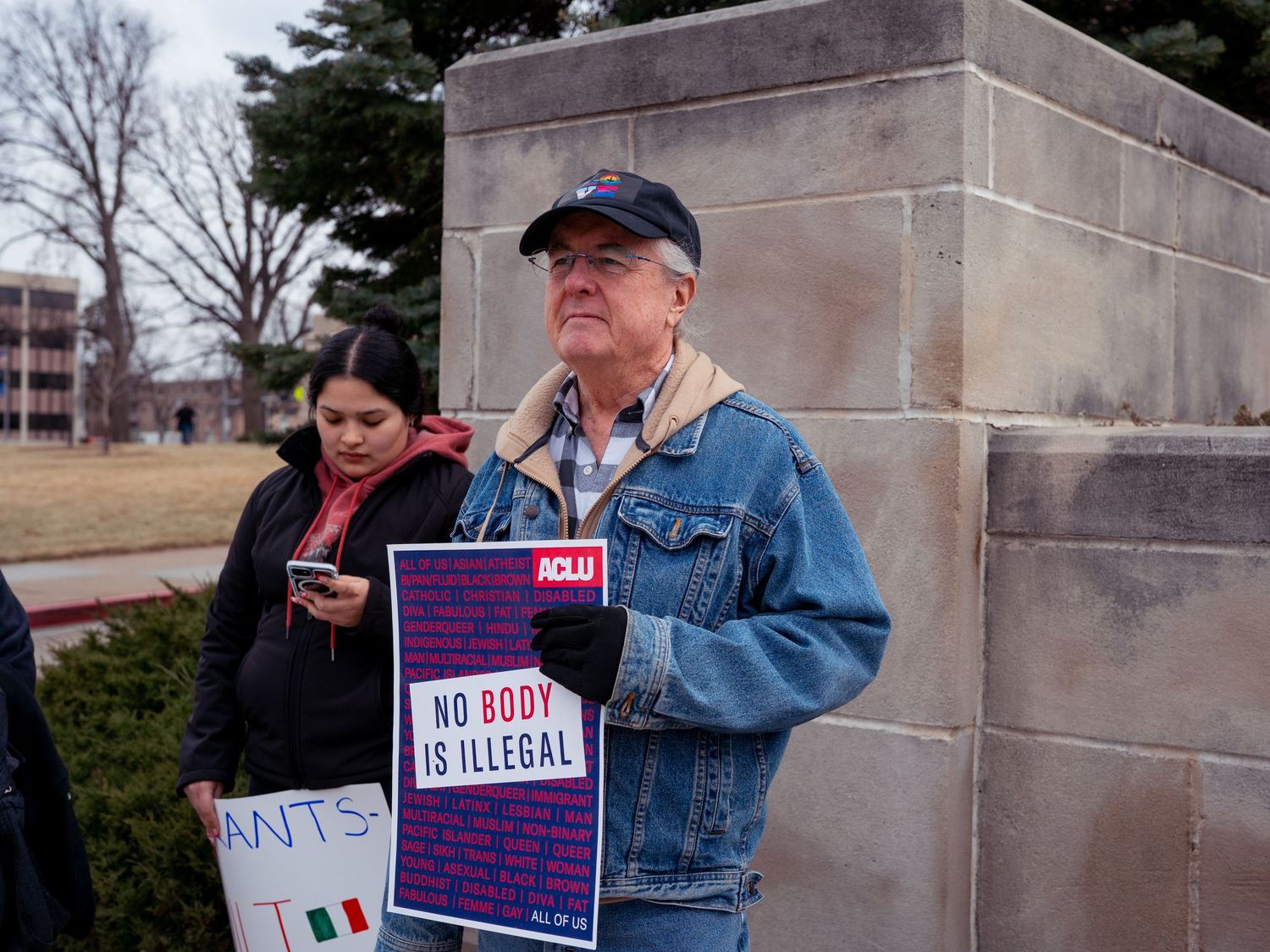 Protesters holding signs gather outside a government building during a demonstration.
