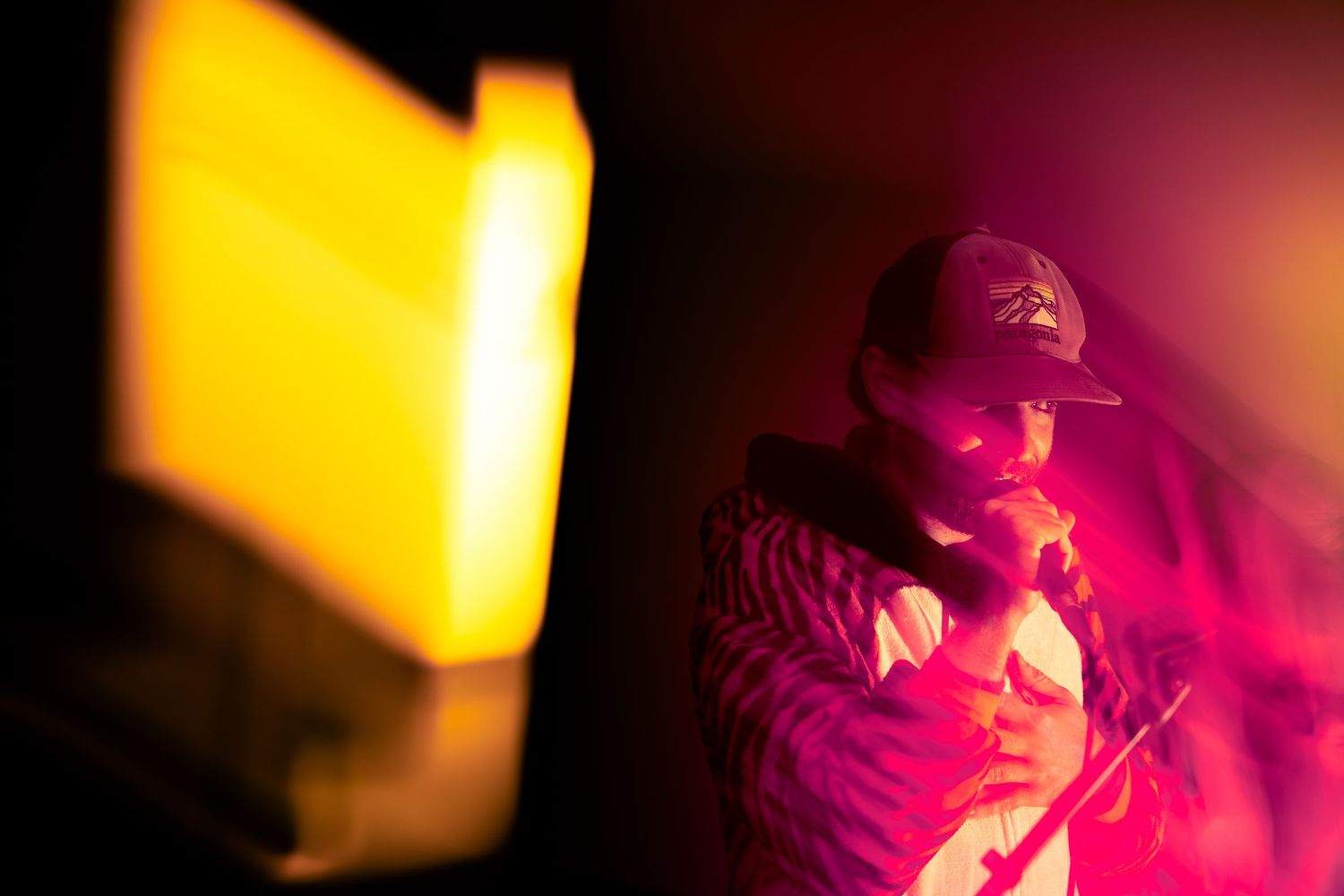 Performer bathed in dramatic red and yellow stage lighting during nighttime concert.