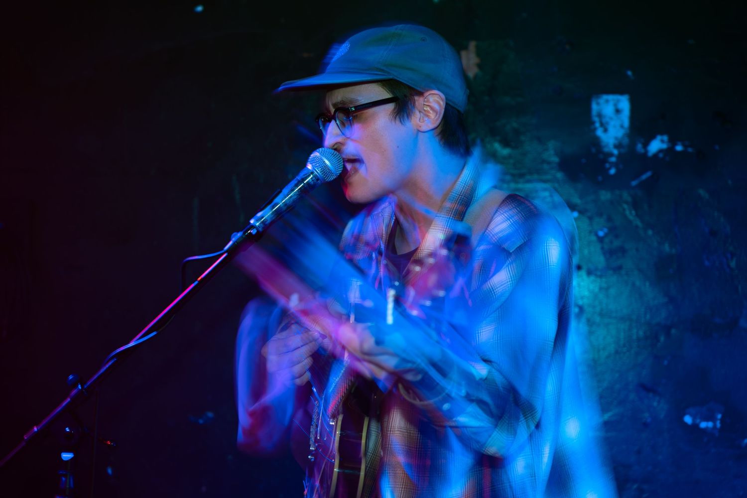 Concert performers on stage bathed in dramatic blue lighting during a live music performance.