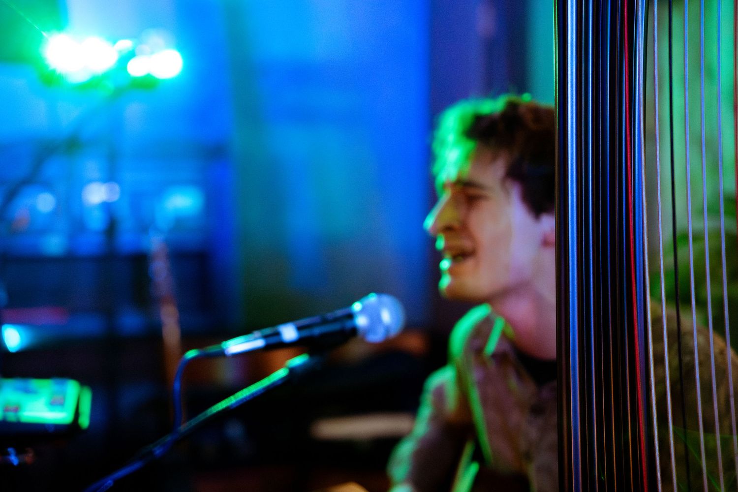 Blue and green stage lights create a moody atmosphere during a live performance.