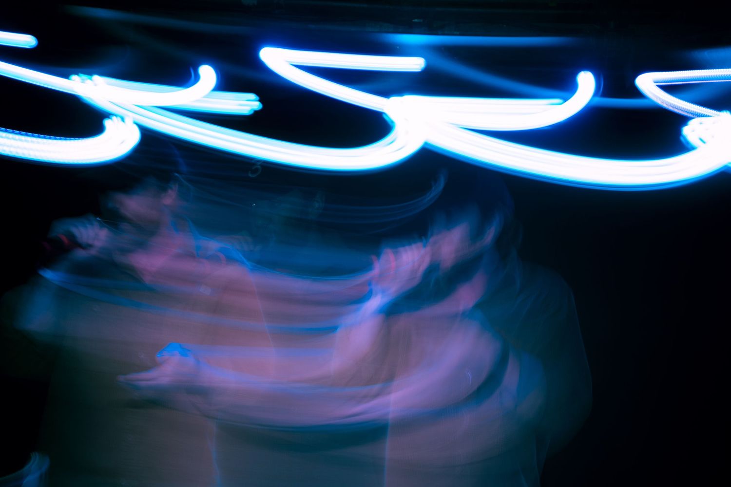 Bright blue light streaks forming curved patterns in darkness.
