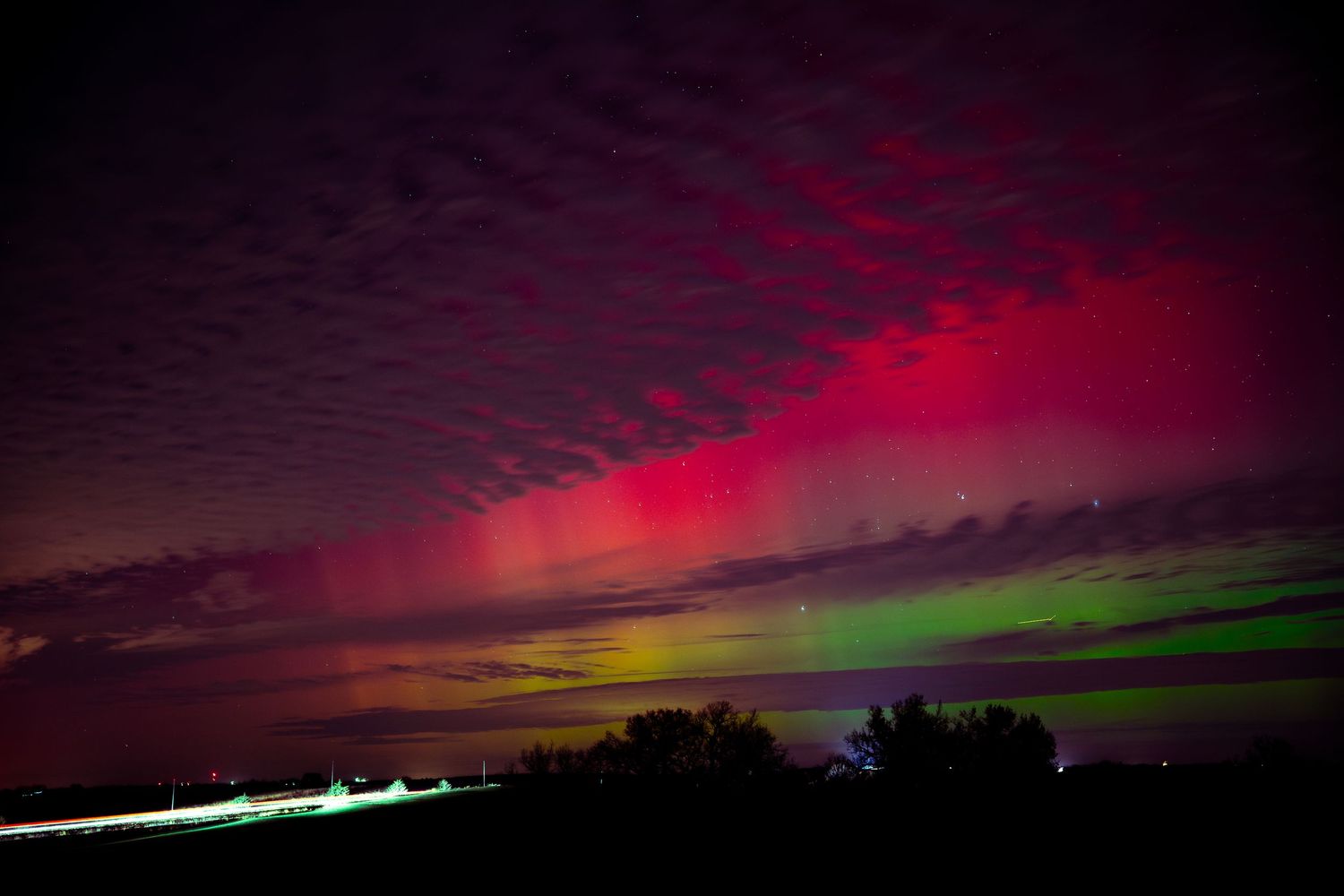 Dramatic red and pink northern lights illuminate the dark horizon in a spectacular natural light show.