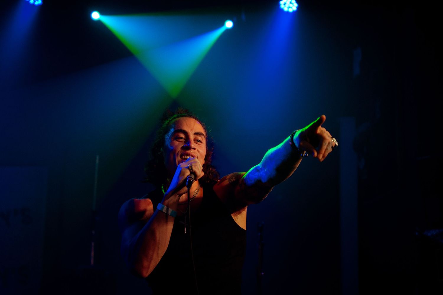 Concert stage lighting creates dramatic blue and green silhouettes during a performance.