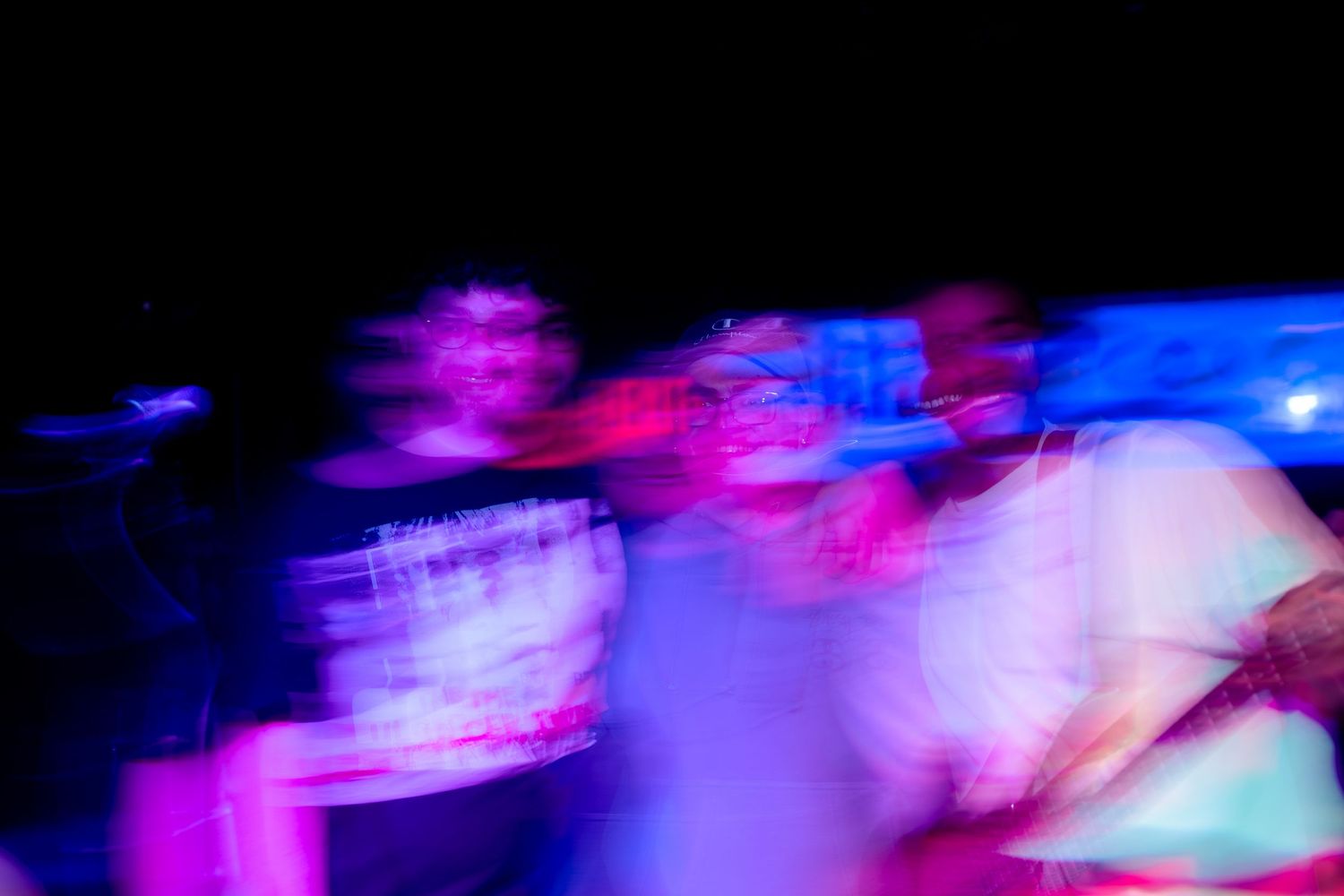 Abstract light painting with vibrant blue and pink streaks creating dynamic motion trails in darkness.
