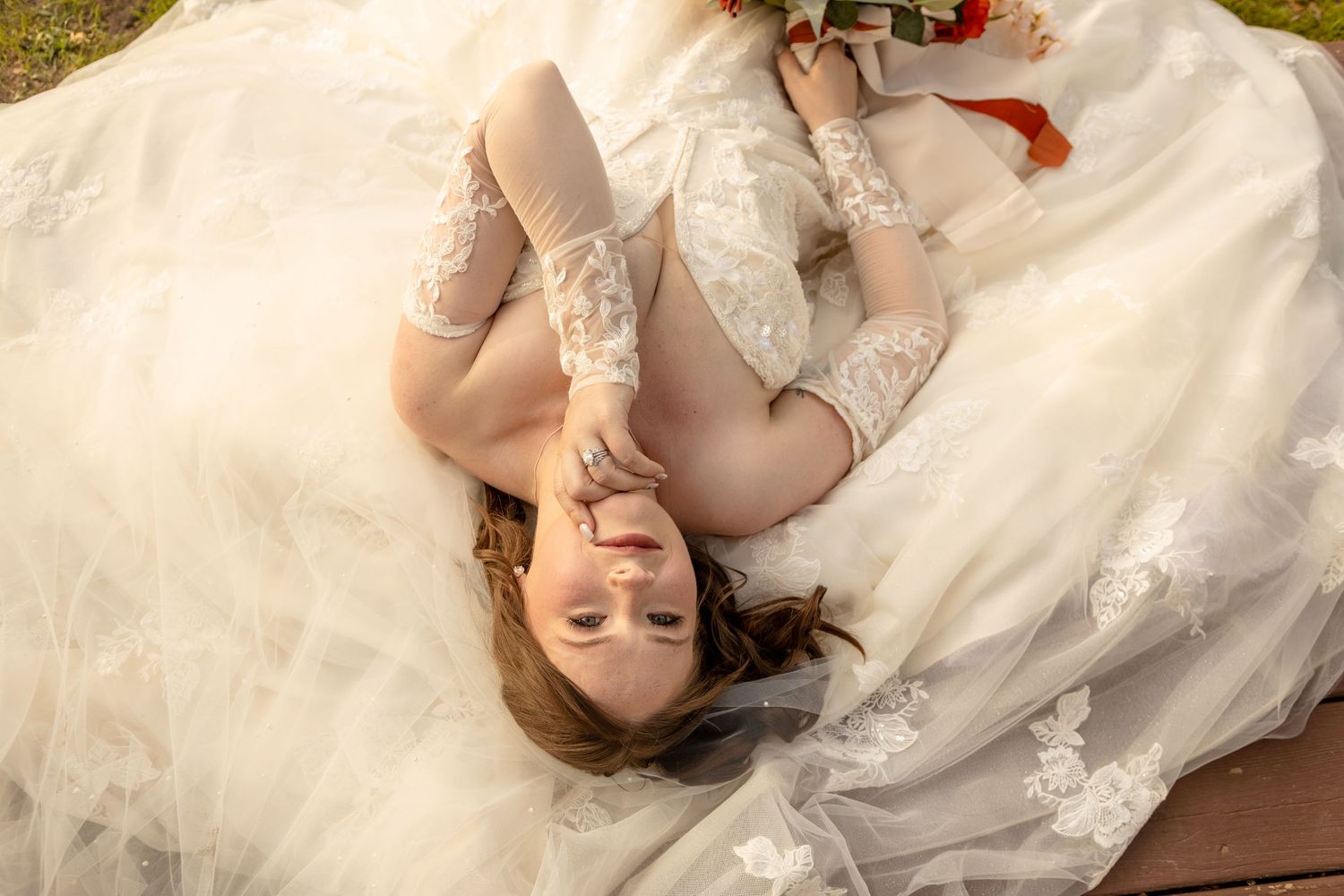 A dreamy bridal portrait with lace details as she lays on white fabric.
