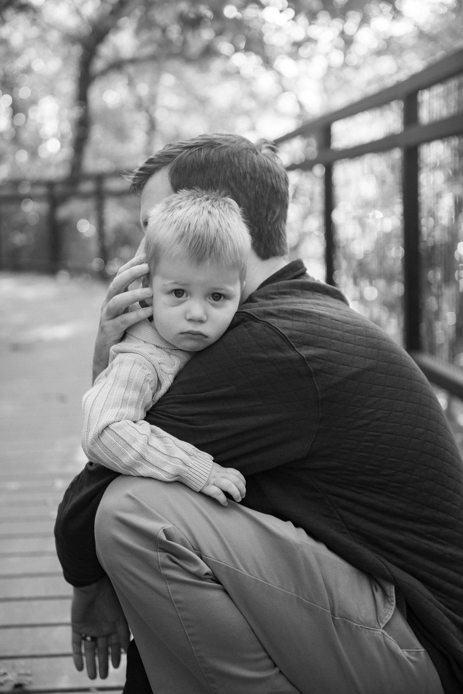Black and white portrait showing tender embrace on wooden bridge walkway.