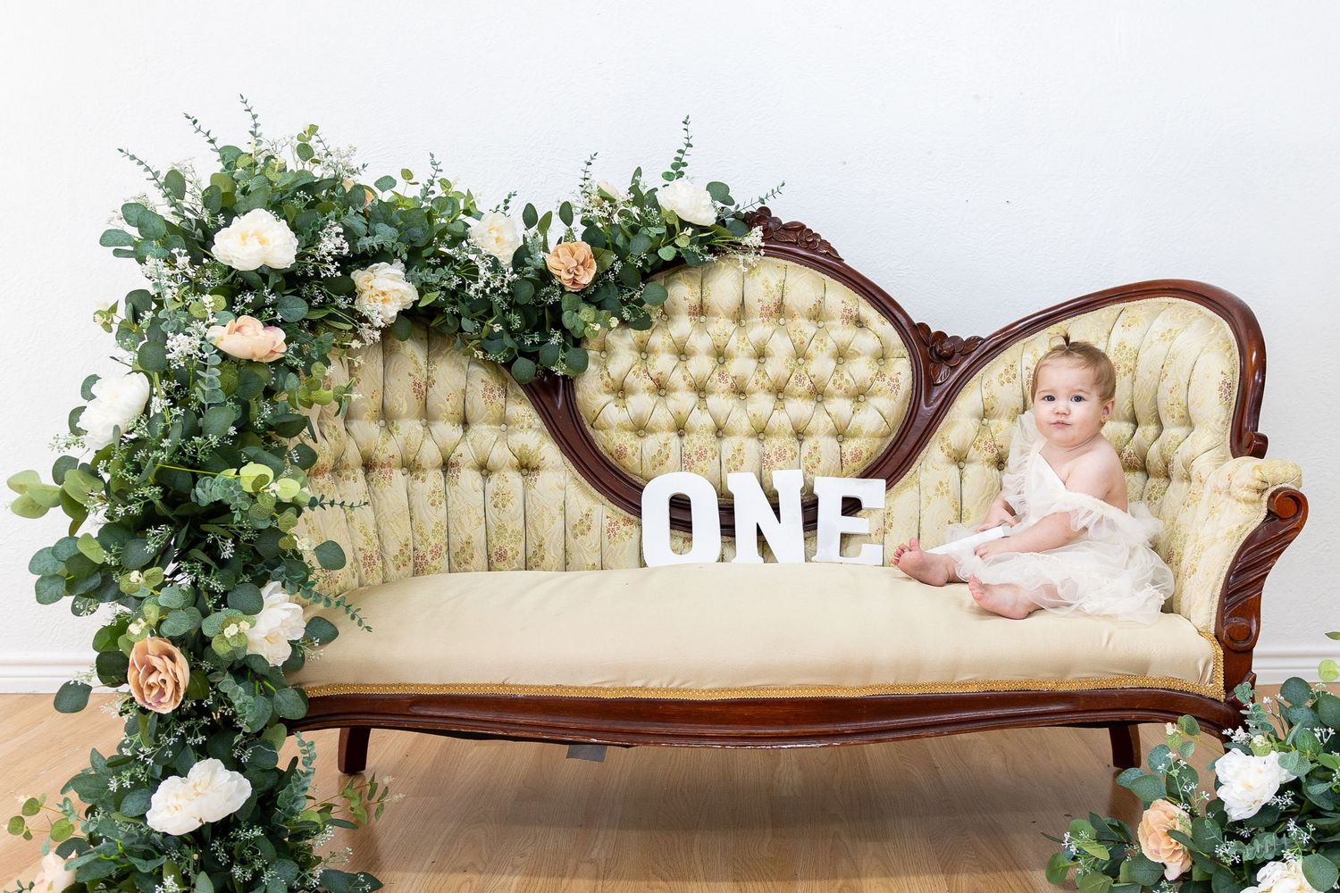 Vintage cream-colored tufted sofa decorated with floral arrangements for photography.