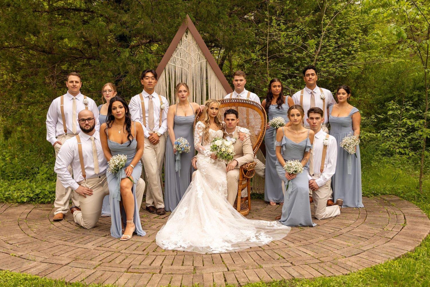 Wedding party poses together in coordinated attire in front of a triangular ceremony backdrop.